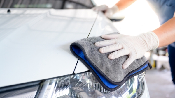 closeup of a gloved hand polishing a grey car with microfiber