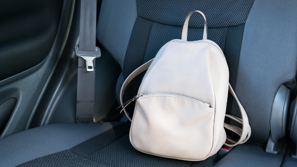 cream-colored backpack sits in the backseat of a car