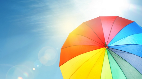 a rainbow-colored umbrella blocks a very bright sun overhead