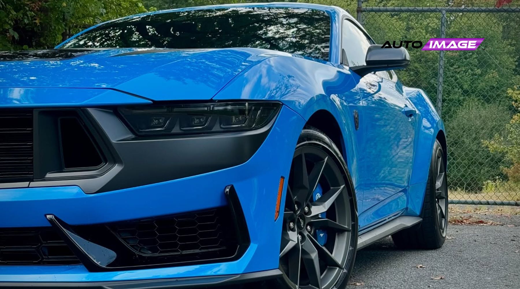 Close-up of a glossy blue sports car treated with ceramic coatings, featuring sharp headlights, a black grille, and clean alloy wheels, emphasizing its sleek, protected finish against environmental damage.