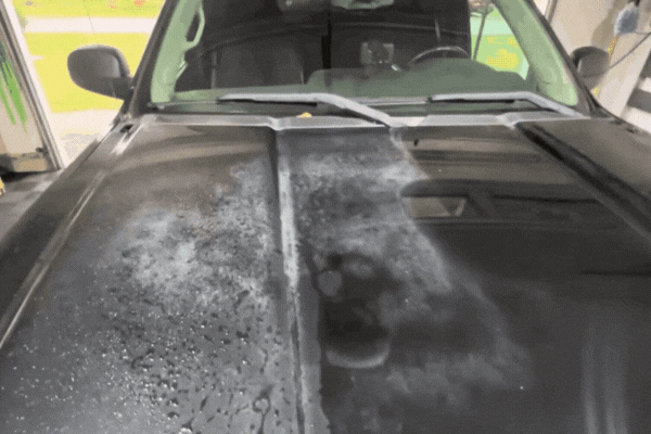 Hood of a black vehicle showing hazy, cloudy paint and trapped moisture caused by premature ceramic coating application before full paint curing, illustrating why fresh paint needs time to cure.