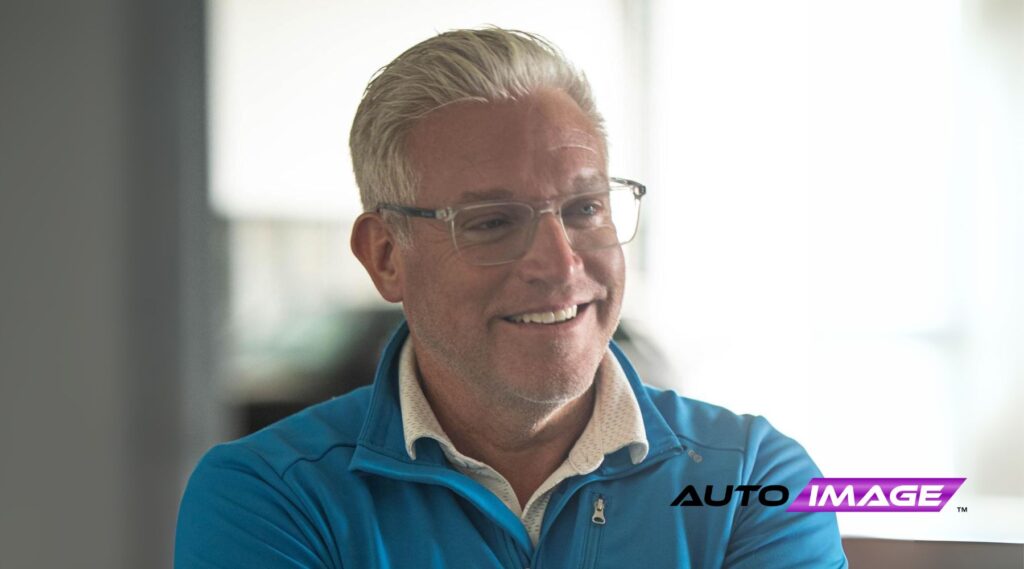 Ryan Warner, new President of LTL Management Group. A middle-aged man with short silver hair and glasses, smiles confidently with arms crossed while wearing a bright blue zip-up jacket over a patterned white shirt. His polished look, including a silver watch and wedding band, reflects his professional yet approachable leadership style.