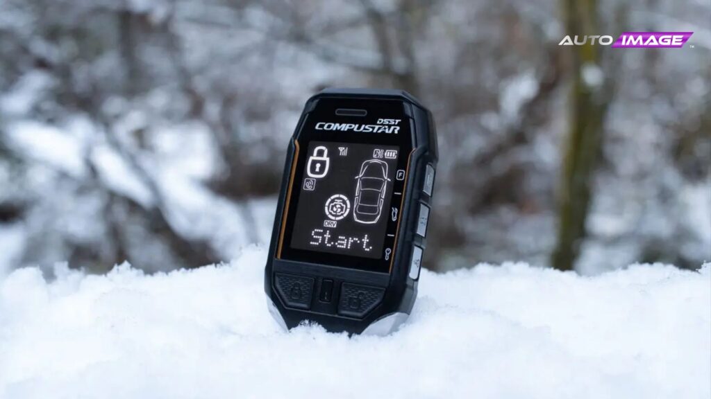 Compustar DSST remote start remote standing upright in fresh snow, screen showing “Start” and vehicle status.