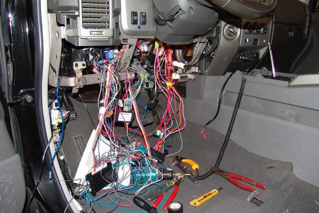 xposed vehicle dashboard with a tangle of wires and installation tools during a remote start installation, showing the complex wiring process that affects remote start installation costs in New Jersey.
