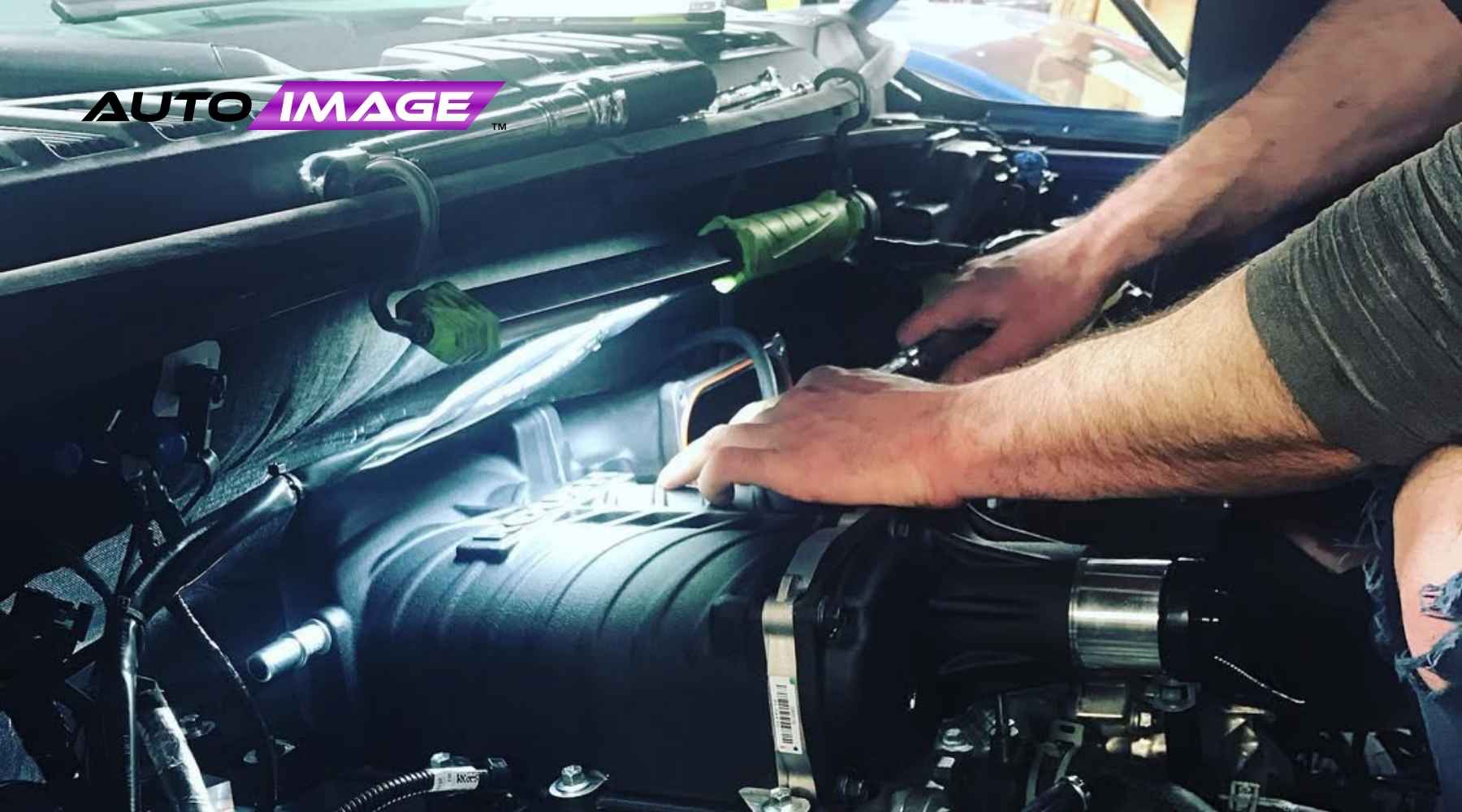 Technician working under the hood of a vehicle during a remote start installation at Auto Image in New Jersey, showcasing hands-on expertise.