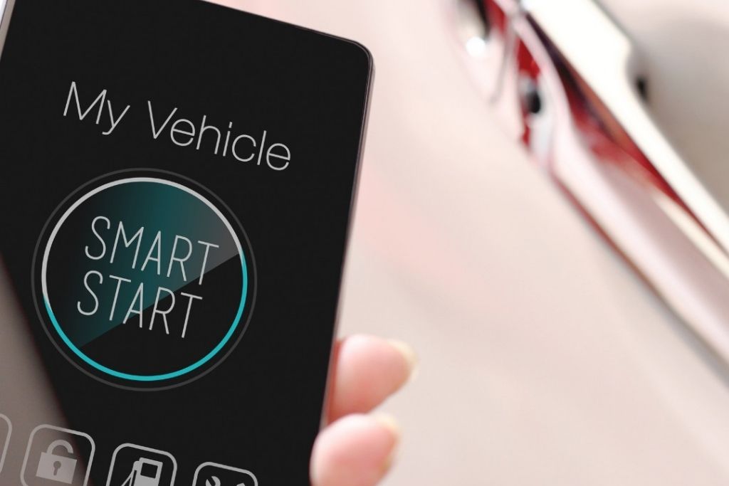 A smartphone screen displays a “SMART START” button under the label “My Vehicle,” indicating remote vehicle control via mobile app. The image visually supports Auto Image’s discussion of how smartphone-based features influence remote start installation cost in New Jersey.